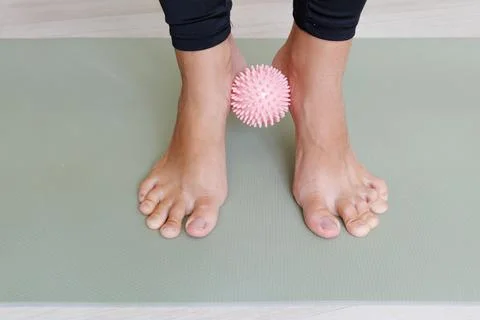 Preventive foot exercise squeezes a massage ball between the ankles to train Stock Photos