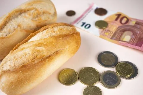 Price of bread, white bread loaf with euro money and coins. Expensive food Stock Photos