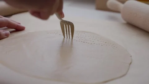 Pricking rolled dough with a fork on kitchen surface, with rolling pin nearby Vídeos de archivo 340481834