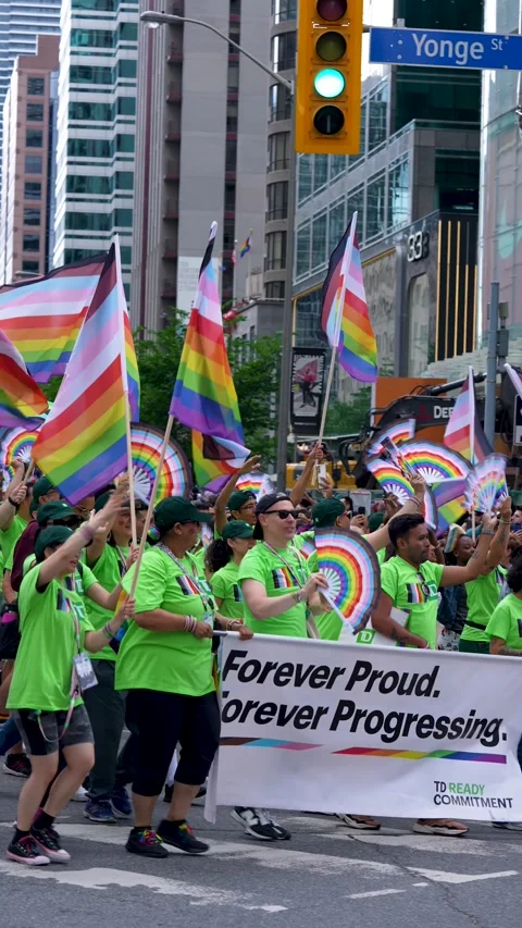 Pride Parade Participants with Rainbow Flags and Corporate Banner Toronto Stock-Footage 332018075