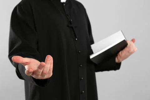 Priest with Bible praying on grey background, closeup Stock Photos