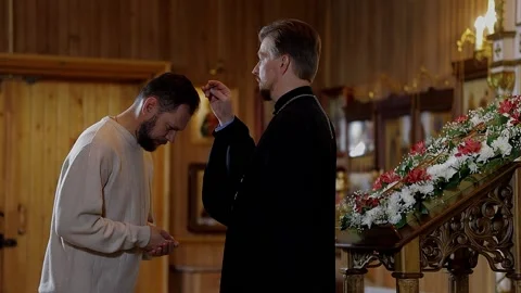 A priest blesses a bearded man in an Orthodox church after a festive church mass Видео 162464153
