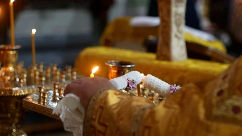 A priest in a cassock sets fire to two beautiful candles. Stock-Footage 119976696