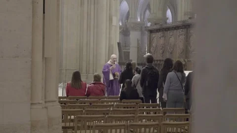 A priest leads a congregation during a religious service inside the Notre Dame Stock Footage 306442680