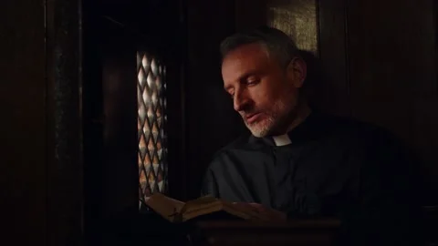 The priest listens to confession while sitting in the confessional. A pastor Stock Footage 235185697