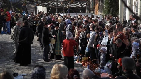 Priest pours holy water over the heads of people. with baskets with Easter cakes Stock Footage 123710219