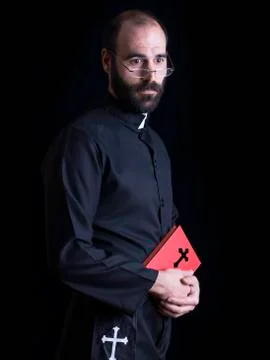 Priest praying with a bible, looking at camera Stock Photos
