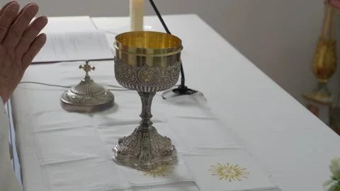 Priest raises hands over gold chalice on altar during mass Stock Footage 346111140