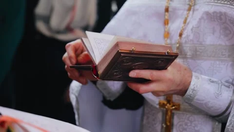 A priest reads a prayer while holding a Bible in his hands Stock Footage 334744381