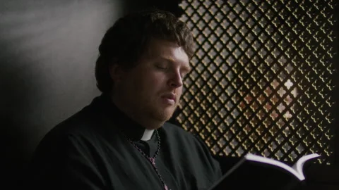 Priest Sitting in Confessional Booth, Reading Scripture from Bible Stock Footage 318340117