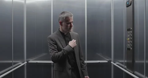 Priest takes the elevator and pushes a button Stock Footage 307321404