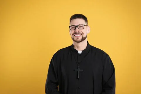 Priest wearing cassock with clerical collar on yellow background Stock Photos