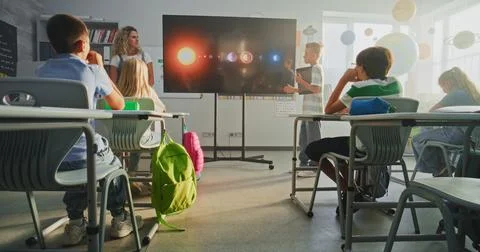 Primary School Boy Showcasing Knowledge of Astronomy in Front of Class and Stock Photos