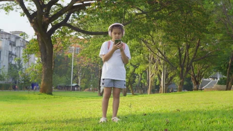 Primary school girl using smartphone in the park, Digital learning concept. Vidéo 334271527