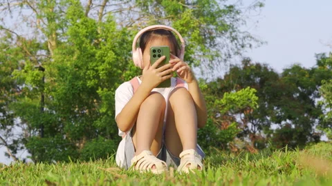 Primary school girl using smartphone in the park, Digital learning concept. Vidéo 334271549