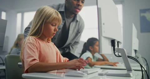 Primary School Girl Working on Computer. Teacher Guiding Young Student in Stock Footage 316298671
