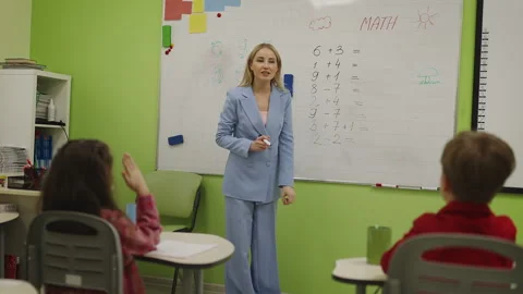 Primary school pupils raising hands answering math questions in classroom Stock Footage 333586235