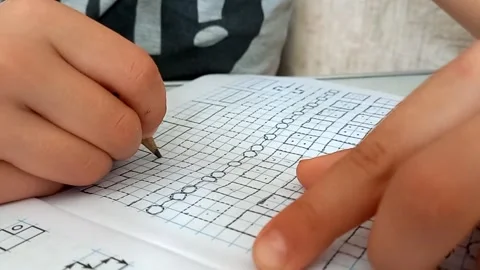Primary school student carefully traces patterns with pencil in notebook. Video stock 304707420