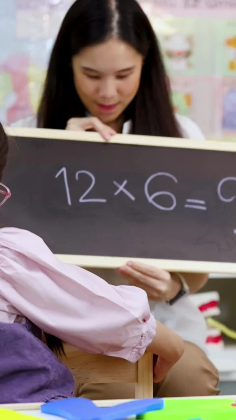 Primary School Student Solving Multiplication Problems with Teacher Stock Footage 329216146