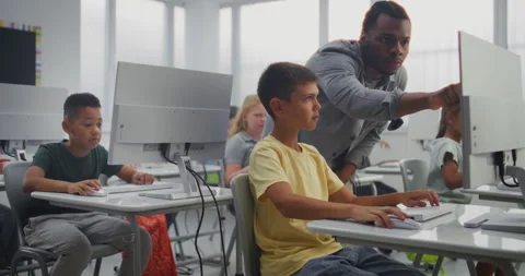 Primary School Students Working on Computers. Teacher Guiding Young Boy in Stock Footage 316293977