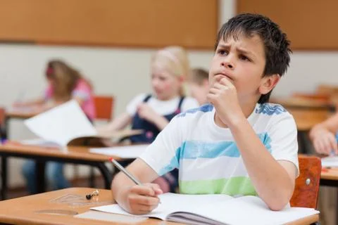 Primary student sitting at desk thinking Stock Photos