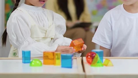 Primary Students Learning Geometry with Colorful 3D Shapes in Classroom Stock Footage 330102392