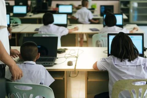 Primary Students study by computer in classroom. Stock Photos