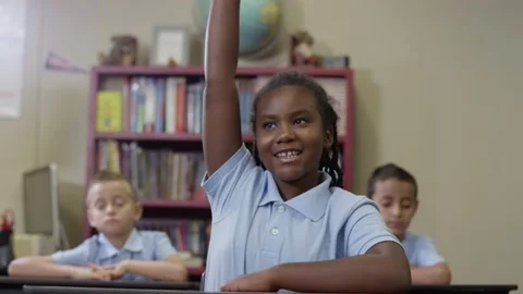 Primary students in uniforms sit in class as happy black girl raises her hand Stock Footage 141757714