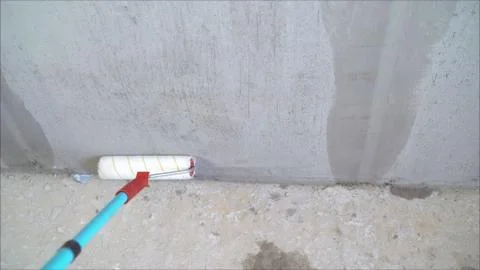 Primer application by roller. The house is under construction. Worker puts a  Stock Photos