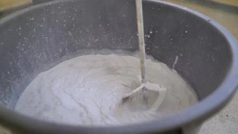 The primer is mixed in a large bucket using a construction mixer. The mixer i Stock Photos