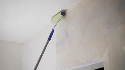 The primer solution is applied to the wall using a roller, so as to remove du Stock Photos