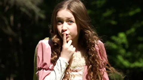 A princess puts her finger to her lips, sharing a secret outside in nature Stock Footage 44116201
