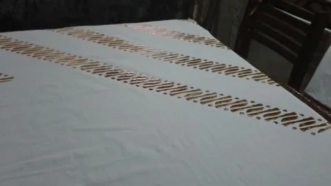 Printed batik craftsmen creating a pattern on a fabric using a stamp for Stock Footage 153444532