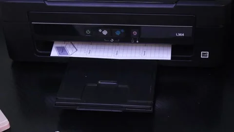 Printer In Action. Paper sheet being printed slowly from black printer Stock Footage