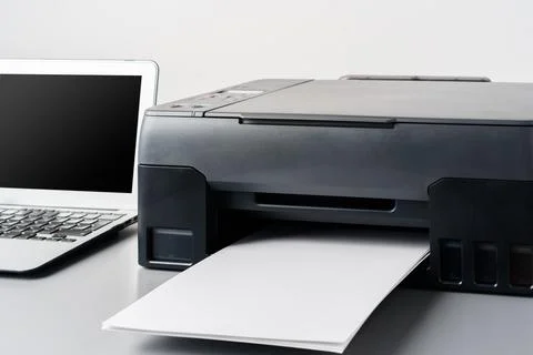 Printer and laptop on grey table in office Stock Photos