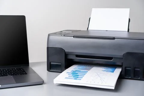 Printer and laptop on grey table in office Stock Photos