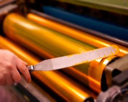 PRINTER APPLYING INK TO ROLLERS OF PRINTING PRESS Stock Photos