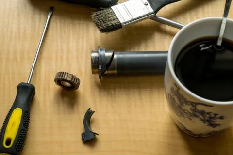 Printer parts, tools, grease, broken gear and coffee mug on the table Stock Photos