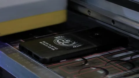 Printer is printing branding information onto black phone case - close up 動画素材 347245335