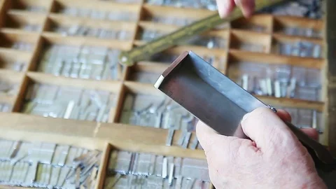 Printer sets letterpress type on composing stick Stock Footage