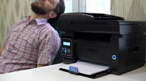 The printer on the table printed the word wake up to the sleeping man beside him Stock Photos