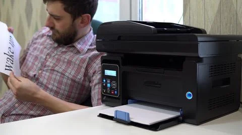 The printer on the table printed the word wake up to the sleeping man beside him Stock Photos