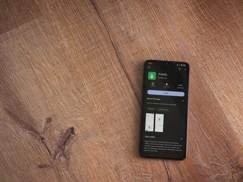 Printify app play store page on smartphone on wooden background Stock Photos
