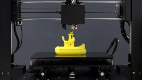 Printing on 3D printer figurines toys ship from yellow plastic close-up Stock Footage 105268968