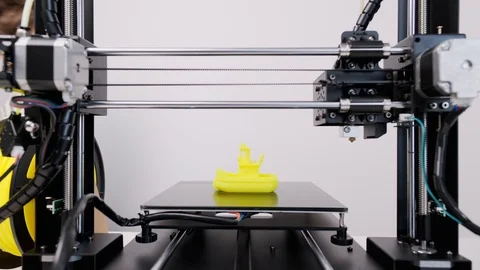 Printing on 3D printer figurines of toys from white plastic. The boy happily Stock Footage 105268974