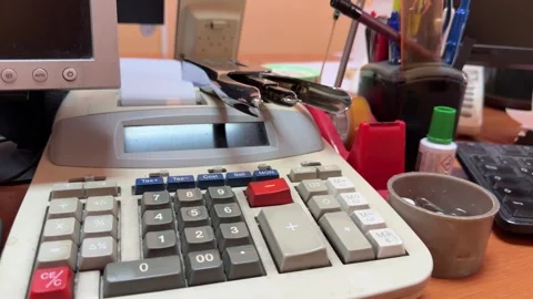 Printing calculator and binder clip resting on cluttered desk Stock Footage 337576868