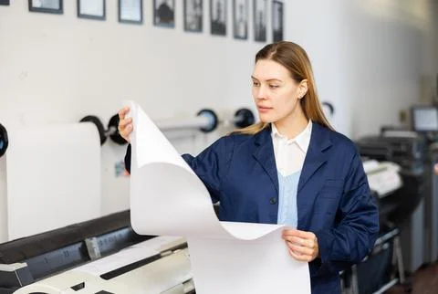 Printing establishment worker examining large piece of paper Stock Photos