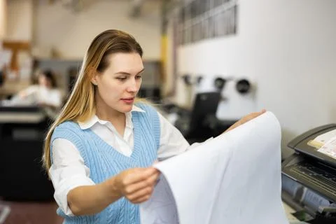 Printing establishment worker examining large piece of paper Fotos de archivo