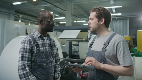 Printing Factory Engineer Using Tablet and Discussing Machinery with Colleague Stock Footage 335483644