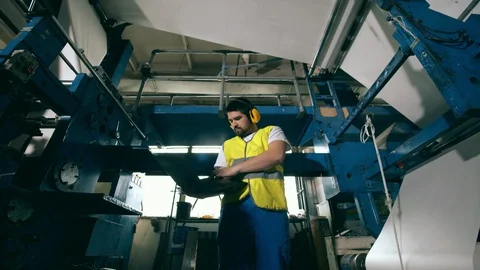 Printing factory worker is examining functioning equipment. Engineer, worker at Video stock 126010322